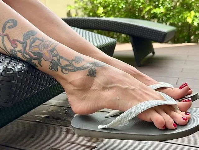Neue Flip-Flops an meinen hübschen Füßen mit langen Zehen im Freien, rot lackierte Fußnägel