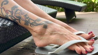 Neue Flip-Flops an meinen hübschen Füßen mit langen Zehen im Freien, rot lackierte Fußnägel