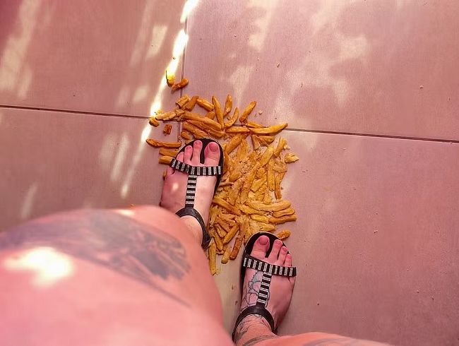 Pommes frites in flachen Sandalen zerdrücken