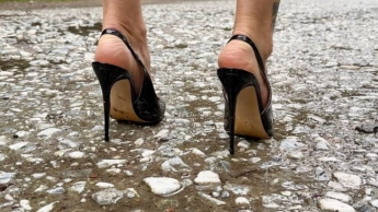 Schwarze klassische Stiletto High Heels ohne Ferse, 12 cm Absätze und im Wald, tief im Gras, auf der Straße