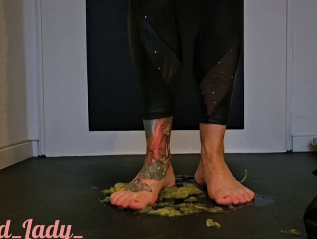 In High Heels und mit nackten Füßen Weintrauben klein treten