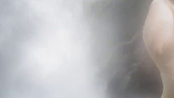 Sie zieht sich am Wasserfall im Freien aus