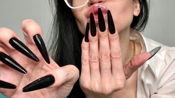 Lange schwarze Fingernägel und ein heißes Outfit mit Dessous, schwarzen Strümpfen, Bleistiftrock und weißer Bluse